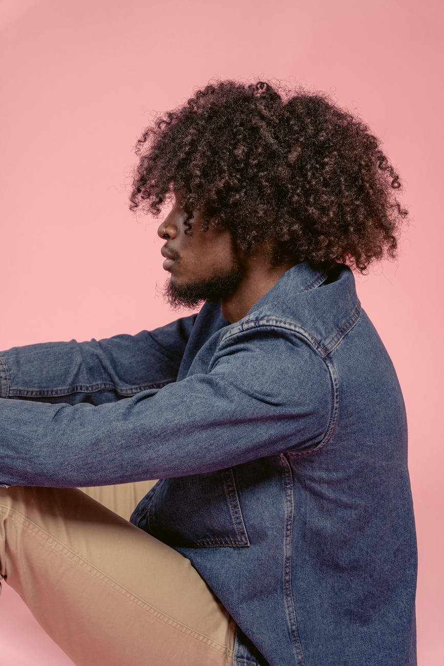 serious black man in denim jacket sitting in studio